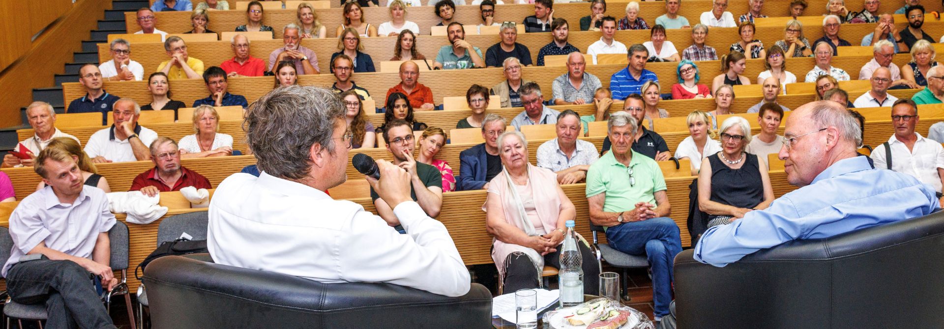 Gregor Gysi im Gespräch mit Jura-Dekan Benjamin Lahusen in einem vollen Hörsaal der Viadrina
