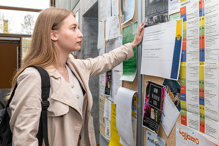 Viadrina-Studierende-liest-Aushaenge-auf-schwarzem-Brett