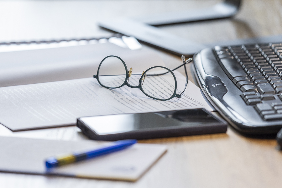 Arbeitsplatz in Großaufnahme, Notizbuch, Tastatur, Büro, Handy, Brille Arbeitsplatz in Großaufnahme, Notizbuch, Tastatur, Büro, Handy, Brille