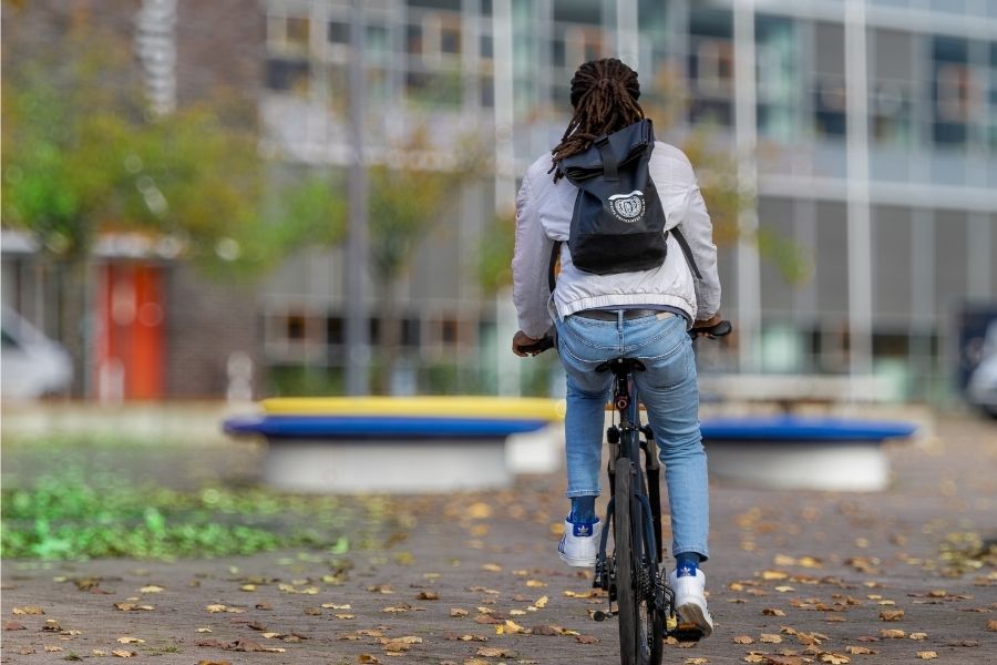 Person mit Viadrina-Rucksack radelt über den Viadrina-Campus