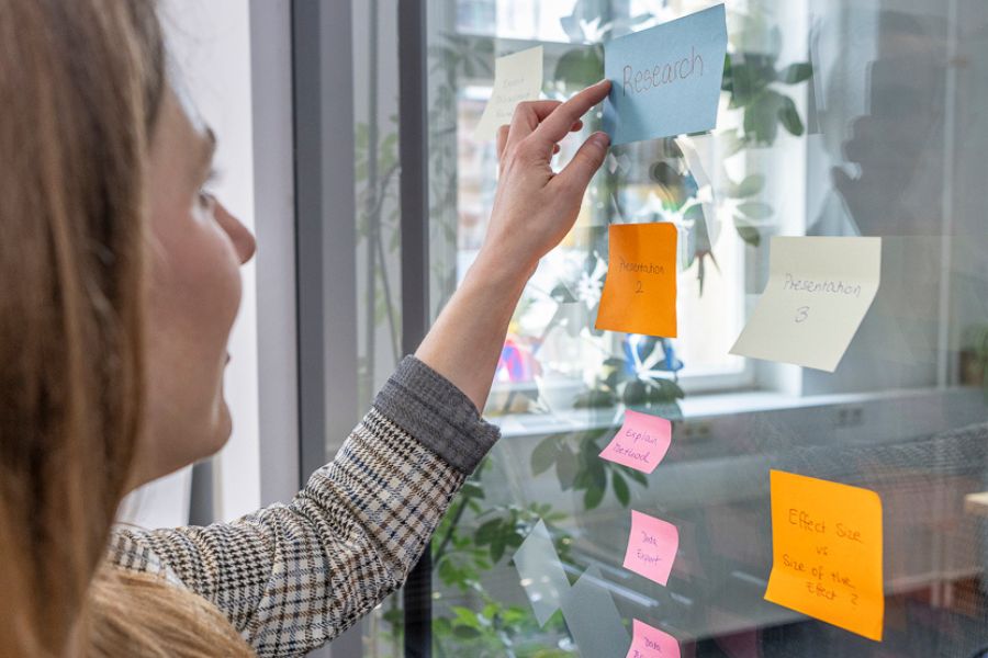 Studentin klebt "Research" Aufkleber auf das Glas, Brainstorming, Notizen machen