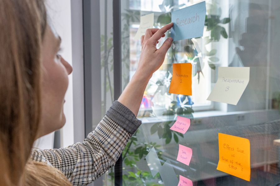 Studentin klebt "Research" Aufkleber auf das Glas, Brainstorming, Notizen machen Studentin klebt "Research" Aufkleber auf das Glas, Brainstorming, Notizen machen